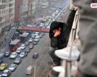 圖為2014年1月3日，蘭州，6名農(nóng)民工為了討薪爬上白銀路一居民樓9樓平臺要“跳樓”。原來，該樓4層的甘肅天安建筑機械工程公司拖欠24名工人的24萬元工錢，他們討要5個月毫無結(jié)果，便做出危險之舉。后經(jīng)有關部門多方協(xié)調(diào)，工人們當場拿到了18萬元。于永昭/視覺中國