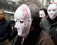 近幾年，由于經(jīng)濟增速下行，中西部地區(qū)和中小城市成為當前討薪矛盾多發(fā)地區(qū)。一邊是國家和地方維護打工者權(quán)益的法律法規(guī)不斷出臺，另一邊則是“年年干活年年欠，年年討薪年年難”。不少打工者不得已只好采取行為藝術(shù)等手段以博取關注。圖為2015年2月2日，西安市尚德路陜西省水利廳的門前，七八位頭戴著白色面具者站在凜凜寒風中，面具上寫著：“含淚討工錢” “無顏見父母”等標語。據(jù)了解，這幾個人是70名農(nóng)民工的代表，他們之前在武功縣干的工程被欠款156萬元。誰知，包工頭不但電話打不通，以前的家也搬了，根本找不到人，多次找到水