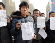 承建商已將工程款給付90%，但包工頭宋林卻把錢拿走不給工人結(jié)工資。一氣之下，十多名工人將包工頭車和人扣下，一不留神卻讓包工頭翻墻跑了。2015年12月31日，在勞動監(jiān)察部門協(xié)調(diào)下達成初步協(xié)議，包工頭將工人手續(xù)移交到成泰公司，由成泰公司替宋林代付一半工資，但在移交工人手續(xù)的時候包工頭害怕再次被扣卻一直不敢露面。1月3日，包工頭給農(nóng)民工發(fā)來短信，并要求寫下承諾書，保證不扣他本人。圖為1月5日，陜西商洛，討薪農(nóng)民工在工地上出示欠條和他們寫給包工頭的承諾書。華商報記者 閆文青/視覺中國