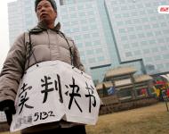 2006年1月24日，在京從事降水井工程的老陳掛著寫有“賣判決書”的紙口袋在北京站口附近來回走著。曾是名小工頭的老陳被欠工程款4萬元，為了給工人們開資不得已賣掉了打井機器。2002年法院宣判老陳勝訴，可四年后該判決仍得不到執(zhí)行，無奈之中老陳只好上演此幕。程寧/視覺中國